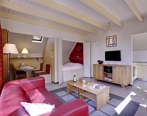 Knusse woonkamer met rode bank in Vakantiehuis Buitenplaats Gerner, Dalfsen, ideaal voor ontspanning.