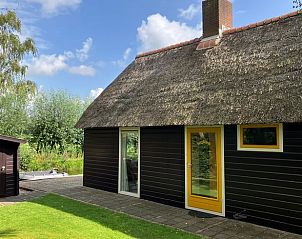 Zijaanzicht van Huisje in Giethoorn, vakantiehuis met rieten dak in de groene omgeving van Overijssel.