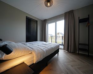 Slaapkamer met groot raam in Chalet in Kampen, een vakantiehuis in Noordwest Overijssel, Overijssel, voor een ontspannen verblijf.