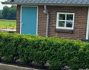 Buitenzijde van Vakantiehuisje in Scheerwolde, Overijssel, met blauwe deur en groene hagen.
