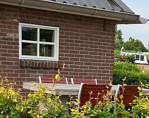 Terras met zitgelegenheid bij Vakantiehuisje in Scheerwolde, omgeven door groen.