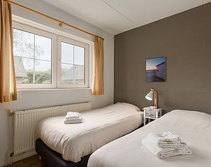 Sfeervolle slaapkamer in vakantiehuis Tjasker Wellness 6, Paasloo, Overijssel, met comfortabele bedden en uitzicht op groene omgeving.
