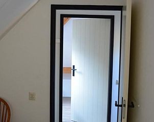 Lichte binnenruimte van Vakantiehuisje in IJhorst met open deur naar slaapkamer.