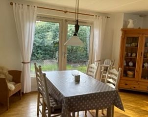 Eetkamer van Vakantiehuis in IJhorst met uitzicht op groene tuin, ideaal voor gezellige maaltijden.