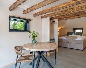 Gezellige binnenruimte van Vakantiehuis in IJhorst, Overijssel met rustieke houten balken en comfortabele slaapkamer.