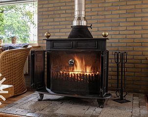 Gezellige woonkamer van OV533 in Eesveen, met comfortabele stoelen en een houtkachel.