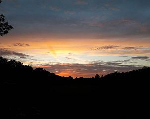 Vakantiehuis in Baars, kleurrijke avondlucht met silhouetten van bomen in Overijssel.