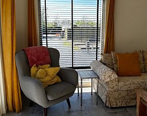 Gezellige woonkamer in Huisje in Abcoude, Utrecht, met comfortabele stoelen en uitzicht op de landelijke omgeving.