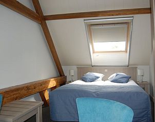 Lichte slaapkamer in Vakantiehuisje in Vreeland, Utrecht met houten balken en groot dakraam.