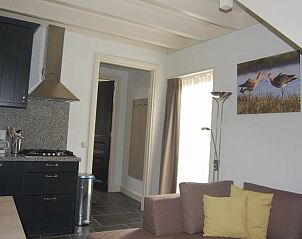 Knusse leefruimte in Huisje in Vreeland, vakantieaccommodatie in Vreeland, Utrecht met kunst aan de muur en veel daglicht.