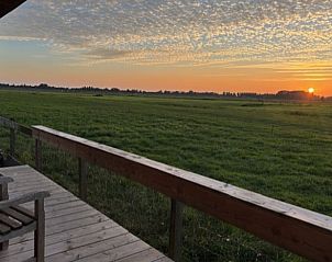 Veranda van Vakantiehuis in Baambrugge met adembenemend uitzicht op de ondergaande zon.