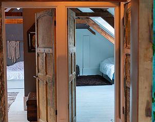 Doorkijk naar slaapkamers in Huisje in Waverveen, vakantiehuis in Utrecht met rustieke deuren.