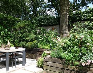 Auenterrasse mit Essgelegenheit am Ferienhaus in Eemnes, Utrecht Nord, umgeben von blhenden Pflanzen.