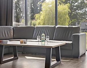 Comfortabele zithoek met glazen schuifdeuren bij Amerongse Berg vakantiehuis in Overberg, Utrecht.