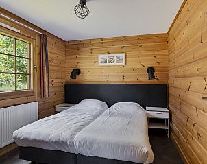 Gemtliches Schlafzimmer in Vakantiewoning Sparrendaal, Doorn, Utrechtse Heuvelrug, mit Holzwnden und einem groen Fenster mit Blick in die Natur.