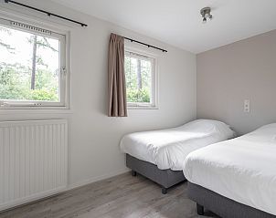 Slaapkamer in Bungalow Schoonoord, Doorn, Utrechtse Heuvelrug, met twee comfortabele bedden en uitzicht op de groene natuur.