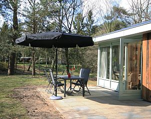 Terras met parasol bij Aangepaste bungalow Sterkenburg, vakantiehuis in Doorn, Utrechtse Heuvelrug, omringd door natuur.