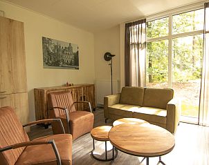 Gezellige woonkamer van Bungalow Zuylestein in Doorn met comfortabel meubilair en uitzicht op de natuur.