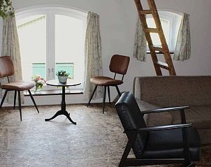 Comfortabele zithoek in Vakantiehuisje in Achterveld, Utrechtse Heuvelrug, met uitzicht op de tuin en houten ladder.