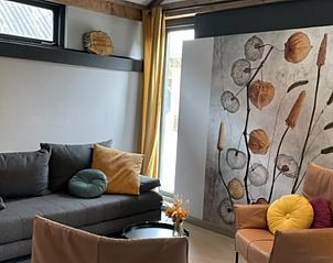 Comfortabele zithoek in Huisje in Oudewater, vakantiehuis in Utrecht met kleurrijke kussens en kunst aan de muur.