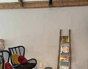 Rustieke leeshoek in Huisje in Oudewater, vakantieverblijf in Utrecht met tijdschriftenrek en moderne stoelen.