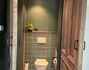 Stijlvol toilet in Huisje in Oudewater, vakantiewoning in Utrecht met houten deuren en groene tegels.