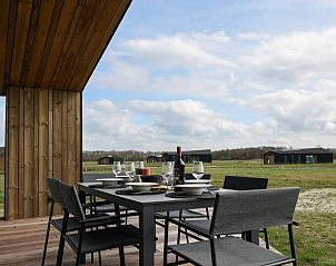 Outdoor terrace of Holiday Home in Wissenkerke offers panoramic views of the green surroundings of North Beveland, Zeeland.