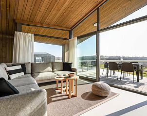 Lichte woonkamer in Vakantiehuisje in Wissenkerke, Noord-Beveland, Zeeland met uitzicht op het terras.