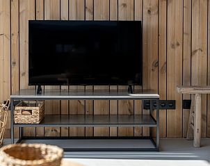 Moderne tv-hoek in Vakantiehuisje in Wissenkerke, Noord-Beveland, Zeeland met houten muur.