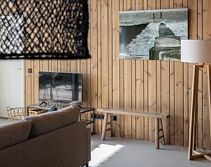 Gezellige woonkamer in Vakantiehuisje in Wissenkerke, Noord-Beveland, Zeeland met tv en kunst aan de muur.