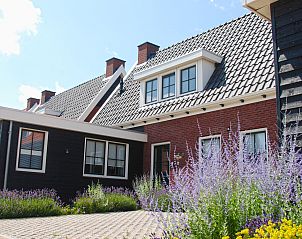 Auenansicht des Ferienhauses Ganuenta in Colijnsplaat, Nord-Beveland mit bunten Blumen und traditioneller Architektur.