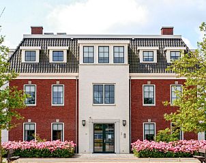 Charmante buitenkant van Appartement Ganuenta in Colijnsplaat, Noord-Beveland, met rode bakstenen en bloeiende bloemen.