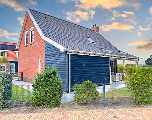 Charmante buitenkant van Dune Design vakantiehuis in Colijnsplaat, omringd door groene hagen.