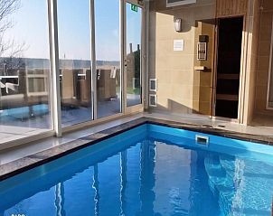 Binnenzwembad in Villa Aqua de Luxe, vakantiehuis in Colijnsplaat, Zeeland met uitzicht op de tuin.