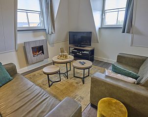 Gezellige woonkamer van Sauna Zee 27H in Colijnsplaat, Noord-Beveland, met comfortabele banken en een moderne haard.