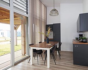 Eetruimte in Bungalow de Dukdalf, Kamperland, met uitzicht op terras en groen landschap.