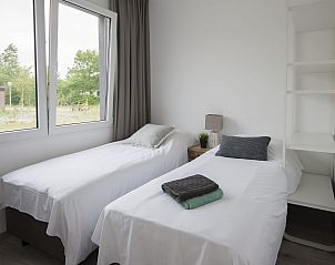 Slaapkamer met twee eenpersoonsbedden in Bungalow de Dukdalf, Kamperland, met uitzicht op de natuur.