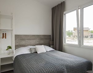 Hoofdslaapkamer in Bungalow de Dukdalf, Kamperland, met comfortabel tweepersoonsbed en grote ramen.