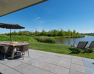 Ruime tuin met ligstoelen aan het water in Duinvallei 32, vakantiehuis in Kamperland, Zeeland.