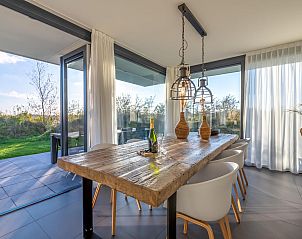 Ruime eetruimte in Duinvallei 39, De Groote Duynen, Kamperland, met moderne stoelen en een glazen wand.