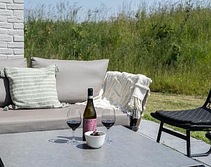 Detail van het terras in Duinvallei 39, De Groote Duynen, Kamperland, met een fles wijn en glazen.