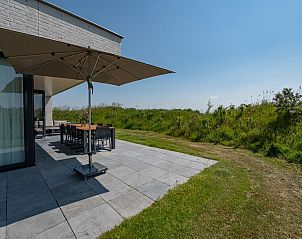 Schaduwrijke plek op het terras van Duinvallei 39, De Groote Duynen, Kamperland, met een grote parasol.