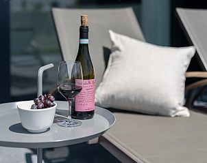 Luxe ligstoelen op het terras van Duinvallei 39, De Groote Duynen, Kamperland, met een fles wijn en druiven.