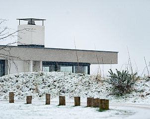 Winterse aanblik van Duinvallei 43, bungalow in De Groote Duynen, Kamperland, omgeven door sneeuw.