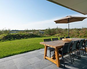 Ruim terras van Duinvallei 43, vakantiehuis in Kamperland, met houten eettafel en uitzicht op het groen.
