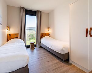 Slaapkamer met twee eenpersoonsbedden in Duinvallei 43, bungalow in Kamperland, met uitzicht op de natuur.