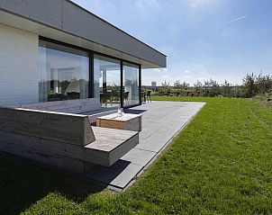 Terras van Duinvallei 43, bungalow in Kamperland, met houten bank en uitzicht op het groen.