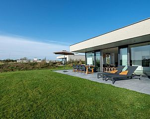 Zijaanzicht van Duinvallei 43, vakantiehuis in Kamperland, met terras en ligstoelen in de zon.