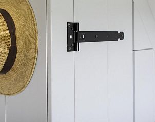 Detail van een hoed aan de muur in VZ2302 Boerderijwoning in Kamperland, vakantiehuis met landelijke charme in Zeeland.