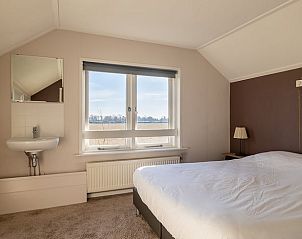 Slaapkamer met groot raam in Vakantiehuisje in Kamperland, Noord-Beveland, met uitzicht op de natuur van Zeeland.